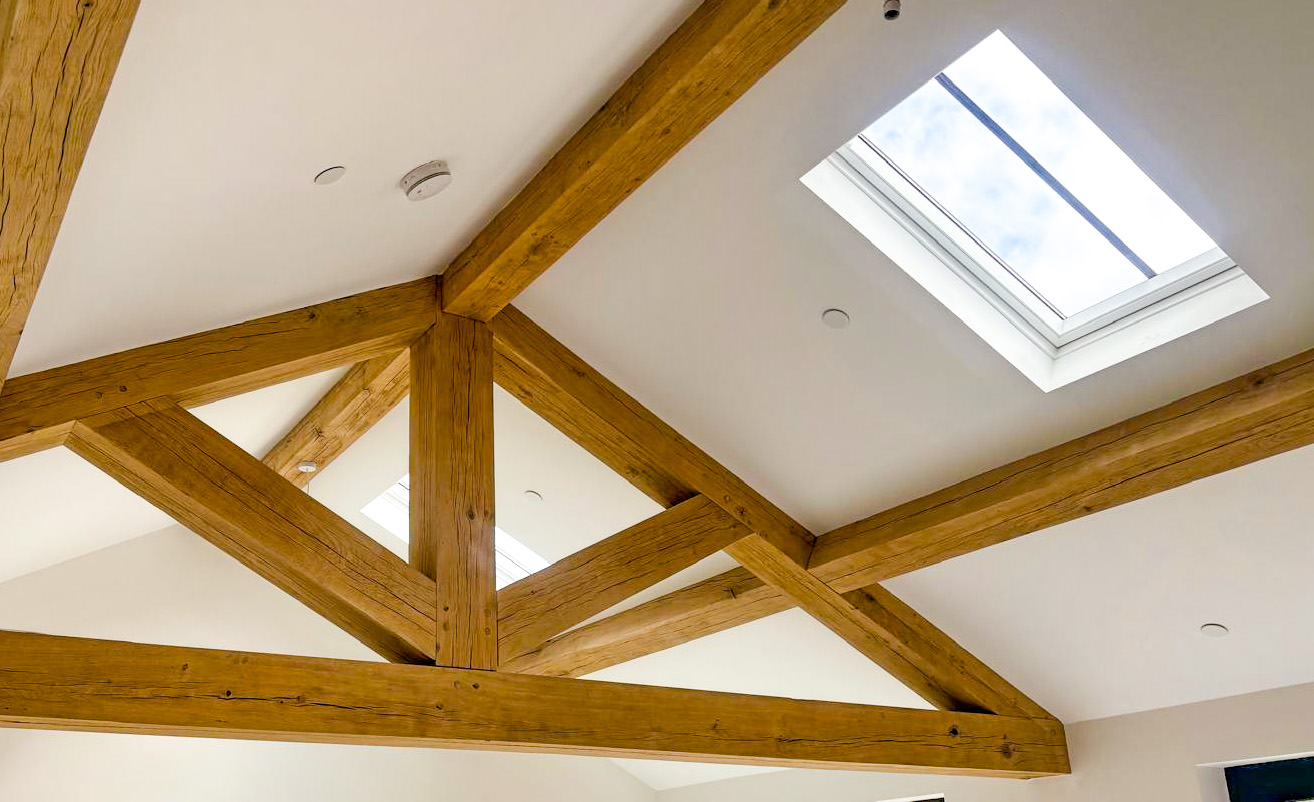 Exposed timber roof trusses in a vaulted ceiling with concealed sprinkler heads fitted flush to the plaster